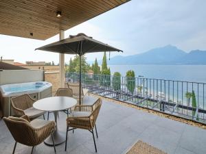 a patio with a table and chairs and an umbrella at Luxury Apartments La Baia - Penthouse in Torri del Benaco