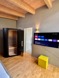 a room with a television and a yellow stool at PaderCityLoft- lichtdurchflutet und privat mit Kamin-Dachterrasse-Sauna-Außendusche im Atrium in Paderborn