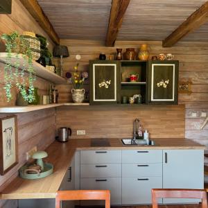 a kitchen with white cabinets and wooden walls at Namelis Bitidė, sodyba Latkrantė, Druskininkai in Latežeris