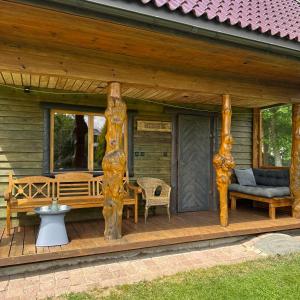a porch of a log cabin with a bench and chairs at Namelis Bitidė, sodyba Latkrantė, Druskininkai in Latežeris +8 photos