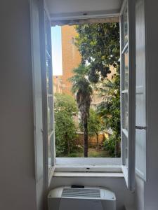 an open window with a view of a palm tree at Hotel Posta - palazzo Guidoni in Orvieto