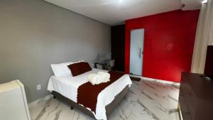 a bedroom with a bed with a red wall at Flat no Centro da Cidade in Parauapebas