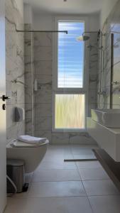 a white bathroom with a window and a tub and a sink at Art Hotel Vlora in Vlorë