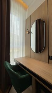 a bathroom with a mirror and a green chair at Art Hotel Vlora in Vlorë