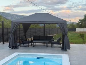 a gazebo with a table and chairs and a pool at Vila Handžić in Mostar