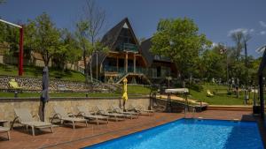 a pool with chairs and umbrellas next to a building at SaguleResort in Monasteri