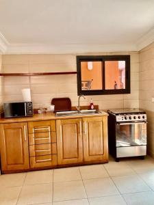 a kitchen with wooden cabinets and a microwave and a stove at Villa Terracotta - Riviera Synacassi - 3 chambres in Abidjan