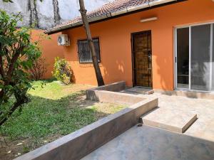 an orange house with a walkway leading to a door at Villa Terracotta - Riviera Synacassi - 3 chambres in Abidjan