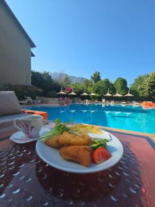 Ein Teller mit Essen auf einem Tisch neben einem Pool in der Unterkunft Balkaya Hotel in Oludeniz