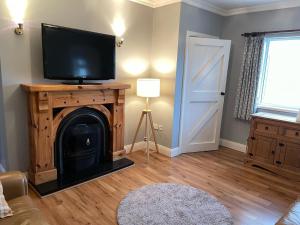 a living room with a flat screen tv on top of a fireplace at Butterfly cottage in Belmullet