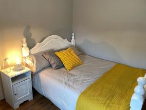 a bedroom with a bed with a yellow pillow on it at Butterfly cottage in Belmullet