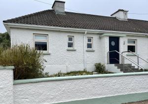 a white house with a blue door and stairs at Butterfly cottage in Belmullet