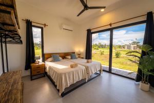 a bedroom with a bed and a large window at Villa Osa Mythica in Puerto Jiménez