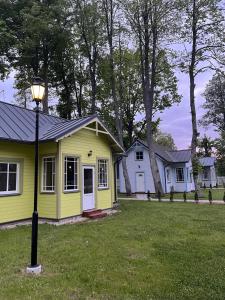 a yellow house with a street light in the grass at Retro Ķemeri in Jūrmala