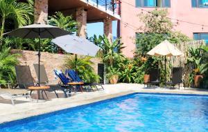 a pool with chairs and umbrellas next to a building at Sayulita Boutique Suites - Pool Access, Kitchen, Walk to Beach in Sayulita