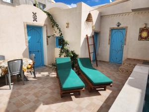 a patio with blue doors and chairs and a table at Houch traditionnelle in Houmt Souk