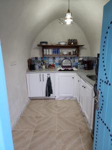 a kitchen with white cabinets and a sink at Houch traditionnelle in Houmt Souk