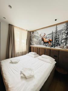 a bedroom with a white bed with a painting on the wall at Apartman 206 in Jahorina