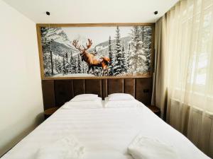 a bedroom with a bed with a painting of a deer at Apartman 206 in Jahorina +5 photos