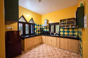 a large kitchen with yellow walls and black counters at Mona's Villa Homestay in Dharmsāla