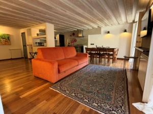 a living room with an orange couch and a kitchen at Luxury Cernaia Home alloggio di charme nel Centro Storico in Genoa