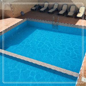 a swimming pool with blue water and chairs at Auberge Bab chellalat in Tamarout