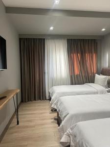 a hotel room with three beds and a window at Hotel EIBA in Peshkopi