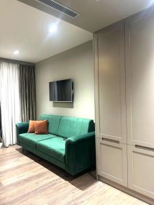 a living room with a green couch and a tv at Hotel EIBA in Peshkopi
