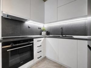 a kitchen with white cabinets and a black stove at L'aTTIQUE in Kastanéa