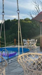 a swing hanging from a porch with a pool at Vikendica Brvnara Marčetić in Banja Luka +25 photos