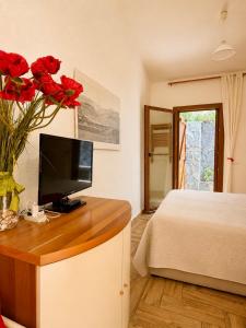 a bedroom with a bed and a vase with red roses at West Sardinia - Bosa in Magomadas