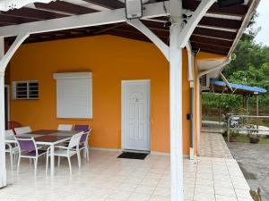 a patio with a table and chairs and a orange wall at Kaz Gwayav Dous in Gros-Morne
