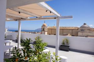 a balcony with white furniture and a view of the city at Palazzo Sorge - Sicilian Charm in Balestrate