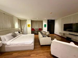 a bedroom with a large white bed and a living room at The Address Boutique Hotel Karachi in Karachi