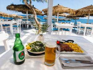 a table with a plate of food and a glass of beer at Perissa Design Centro Suites- BEACH FRONT in Perissa