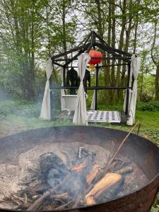 a fire pit with an umbrella and a grill at The Shangri La Sunset Yurt in Tenbury