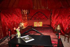 a red room with a bed with a table and a table sidx sidx at The Shangri La Sunset Yurt in Tenbury