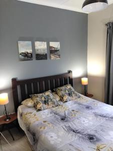 a bed in a bedroom with three pictures on the wall at Garden Route Retreat in George