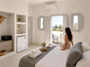 a woman sitting on a bed in a white room at Perissa Design Centro Suites- BEACH FRONT in Perissa +30 photos