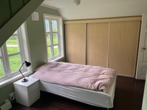 a bedroom with a bed with a lamp and two windows at Feriehus Lærdal in Æri