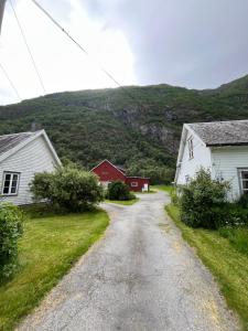 a dirt road with two white houses and a red barn at Feriehus Lærdal in Æri