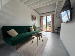 a living room with a green couch and a table at Sunset House Svencele in Svencelė