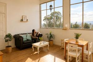 a woman sitting on a couch in a living room at Silvestre Hostel in Pichilemu