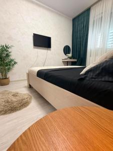 a bedroom with a bed with a tv on the wall at DIAMOND MIRAGE Militari Residence in Chiajna