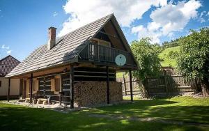 a house with a gambrel roof on a lawn at Chata Reľov in Reľov