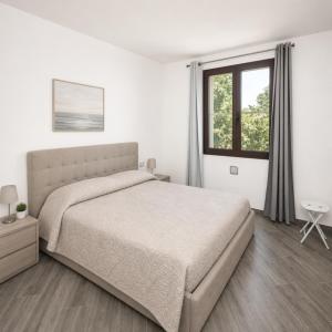 a white bedroom with a bed and a window at Sa lampana in Orosei