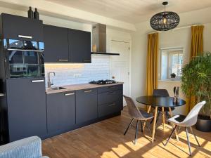 a kitchen with black cabinets and a table with chairs at Recreatieappartement BoerdeRijlst - De Winkel in Sint Nicolaasga