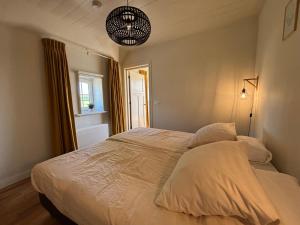 a bedroom with a bed with white sheets and a window at Recreatieappartement BoerdeRijlst - De Winkel in Sint Nicolaasga