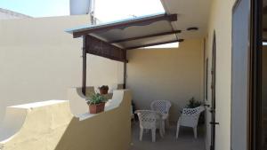 a patio with white chairs and a table and awning at Gozo Apartment - Sannat in Sannat