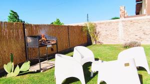a backyard with white chairs and a fire place at La Felita, Tu refugio perfecto en Mendoza in Chacras de Coria